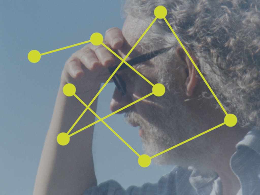 A softly focused portrait of an older person with curly grey hair shielding their eyes with one hand. Bright yellow dots connected by lines are superimposed across the image, forming a geometric network that overlays the figure’s face and body. The contrast between the human subject and the graphic intervention suggests themes of mapping, connection, or data visualisation.